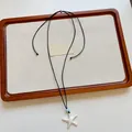 Vista dettagliata di una collana con ciondolo a stella marina su un vassoio decorativo. - Ciondolo Stella Marina con Perline Blu (XL4476A)