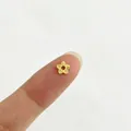 Gros plan d'une petite perle fleur en acier inoxydable doré 18 carats sur le doigt - Style Fleur Texturée à Cinq Pétales (6#)