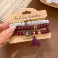 Detail view of 4-piece ethnic beaded bracelet set with tassel and Hamsa hand charm. - Bracelet Style / Four-Piece Set / Purple