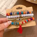 Detail view of bohemian beaded bracelet set featuring Hamsa hand charm and red tassel - Bracelet Style / Four-Piece Set / Red