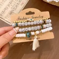 Detail of ethnic beaded bracelet set with hamsa hand charm and white tassel - Bracelet Style / Four-Piece Set / White