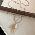 Elegante goldene Halskette mit einem realistischen Muschelanhänger für modebewusste Damen. - Kugelkette mit goldumrandetem Muschel-Anhänger / Goldbraun