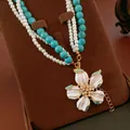 Détail d'un collier multicouche avec perles turquoise, perles et grand pendentif fleur blanche - Collier Fleur Multirang