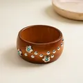 Detailed close-up of a vintage-style wooden bangle with silver floral and rivet accents - Brown