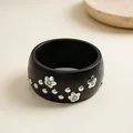 Detail of a vintage black wooden bangle with silver flower studs and turquoise accents. - Black