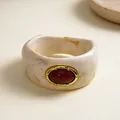 Detail of a vintage marbled resin chunky bangle featuring a central oval red stone inlay - Ivory