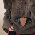 Gros plan d'un étui à lunettes magnétique en cuir marron porté en collier. - Style Magnétique Triangulaire / Marron