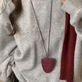 Vue détaillée d'un collier pochette en cuir bordeaux porté sur un sweat-shirt gris - Style Surpiqué en U / Bordeaux