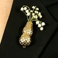 Gold peanut-shaped vase brooch with lily of the valley flowers on a black blazer - Medium KC Gold (09 Med KC Gold N-910)