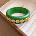 Detailansicht eines grünen Holzarmreifs mit bernsteinfarbenen Acrylperlen im Schmuckkasten. - Grüne Holzmaserung Bernstein Flachperlen / Waldgrün-Bernsteinorange
