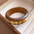 Detaillierte Nahaufnahme eines Vintage-Holzarmbands mit bernsteinfarbenen Acrylperlen - Dunkles Massivholz Bernstein Runder Stein / Dunkelbraun-Hellgelber Runder Stein