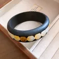 Nahaufnahme eines Retro-Holzarmreifens mit bernsteinfarbenen Acrylperlen-Inlays - Schwarzes Mattes Achat Harz Stil / Schwarz-Bernsteingelb