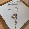 Macro view of a minimalist silver fish pendant necklace with brown leather cord details - Fish Style / Silver and Coffee