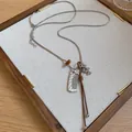 Close-up of a Korean style necklace with a silver comb charm and brown cord on a tray - Comb Style / Silver and Coffee