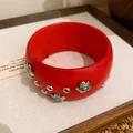 Nahaufnahme eines roten Harzarmreifens mit blumenförmigen Silbernieten und Türkis - Rot Lackierte Metallblütenblatt Türkis / Rot-Metallisches Blumenmuster