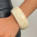 Close-up of a vintage wide cream resin bangle featuring a subtle brown marble tie-dye pattern - Round (WG-0565) / 30mm / White