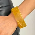 Close-up detail of a vintage amber marble resin wide bangle worn on a model's wrist - Square (WG-0308) / Yellow