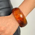 Detailed view of a wide retro marbled resin bangle with amber-toned swirled patterns. - Round (10998) / 30mm / Light Coffee