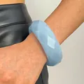 Detail of a light blue faceted acrylic bangle on a wrist - Rhombus (A-1178) / Blue