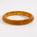 Close-up of amber resin bangle showing marbled texture and twisted design. - Twisted Style (DZ-105) / Light Coffee