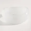 Macro detail view showing the smooth texture of a minimalist wide white resin bangle. - Twisted (M-126) / Clear