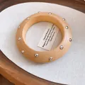 Nahaufnahme eines minimalistischen Holzarmreifs mit silbernen Nieten und natürlicher Maserung - Große Kreisförmige Holz Silbernieten / Holzfarbe-Silberne Nieten
