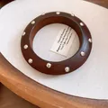 Nahaufnahme eines braunen Holzarmbands im Vintage-Stil mit silbernen Nieten auf Stoff - Vintage Holz Silbernieten / Dunkelbraun-Silberne Nieten