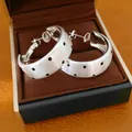 Détail de boucles d'oreilles créoles en argent brossé à pois noirs dans une boîte - Argent (Tige en argent)