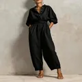 Full-length detail of a black V-neck jumpsuit with buttons and a matching waist belt. - XS / Top And Bottom / Black