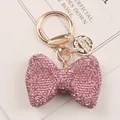 Macro view of pink rhinestone bow keychain with elegant gold-tone clasp detail - Pink