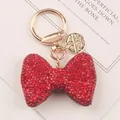 Macro view of a luxury red rhinestone bow keychain with elegant golden clasp and charm - Red