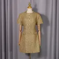 Vue macro détaillée d'une robe en tweed doré avec d'élégants boutons de perles blanches - S / Robes / Or