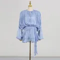Detailed view of light blue pleated mini dress with shimmering fabric and waist tie. - S / Dresses / Blue