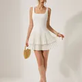 Elegante abito corto bianco con scollo quadrato e gonna a pieghe a balze su modella. - Taglia S / Vestiti / Bianco