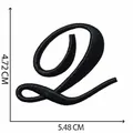 Vista dettagliata della toppa ricamata con lettera corsiva nera per abbigliamento, 5,48x4,72 cm - Lettera Q