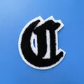 Gros plan sur un écusson lettre C gothique en chenille noire, dimensions 72mm par 60mm - Lettre C (A001)