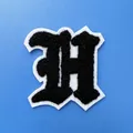 Gros plan montrant la texture de l'écusson brodé en chenille lettre H noir et blanc - Lettre H (A001)