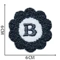 Detailed view of a flower-shaped chenille patch with an embroidered black letter B, 6cm size - Letter B / 6x6cm