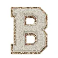 Dettaglio ravvicinato di una toppa in ciniglia bianca lettera B con bordo dorato glitterato - Lettera B / Bianco latte