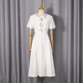 Elegant weißes Midikleid mit Strass-Ausschnitt und Schleifen-Details auf Schaufensterpuppe - S / Kleider / Weiß