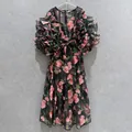 Detail view of a vintage rose print dress with ruffle puff sleeves and waist bow. - Black