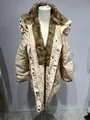 Détail d'un manteau d'hiver beige matelassé avec un grand col en fausse fourrure et capuche. - Abricot