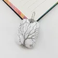 Macro detail of handmade wire-wrapped tree of life on rectangular white gemstone pendant - Howlite