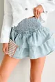 Close-up detail of a light blue denim tiered ruffled mini skirt featuring a smocked waistband - S / Bottoms / Light Blue
