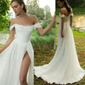 Detailed view of white off-the-shoulder wedding dress with high slit and elegant train. - US2 / White