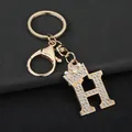 Macro view of a golden rhinestone-encrusted letter H keychain with a mini crown detail - Letter H Decoration (YJ—310) / Gold