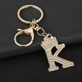 Close-up of sparkling rhinestone initial K keychain with crown on black leather background - Letter K Decoration (YJ—310) / Gold