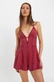 Full-length view of a burgundy denim sleeveless romper with pleated shorts on a model - Burgundy