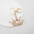 Close-up of a sparkling gold crown keychain with pink pear-shaped crystal - Pink