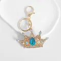 Detailed view of a gold-tone crown keychain with sparkling blue and white rhinestones - Blue